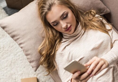 A woman laying and using her phone